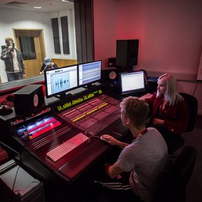 Two students sat at a music mixing desk.