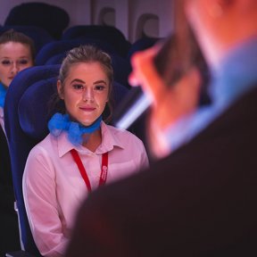 A Travel and Tourism students practicing a safety briefing in the College's mock air cabin.