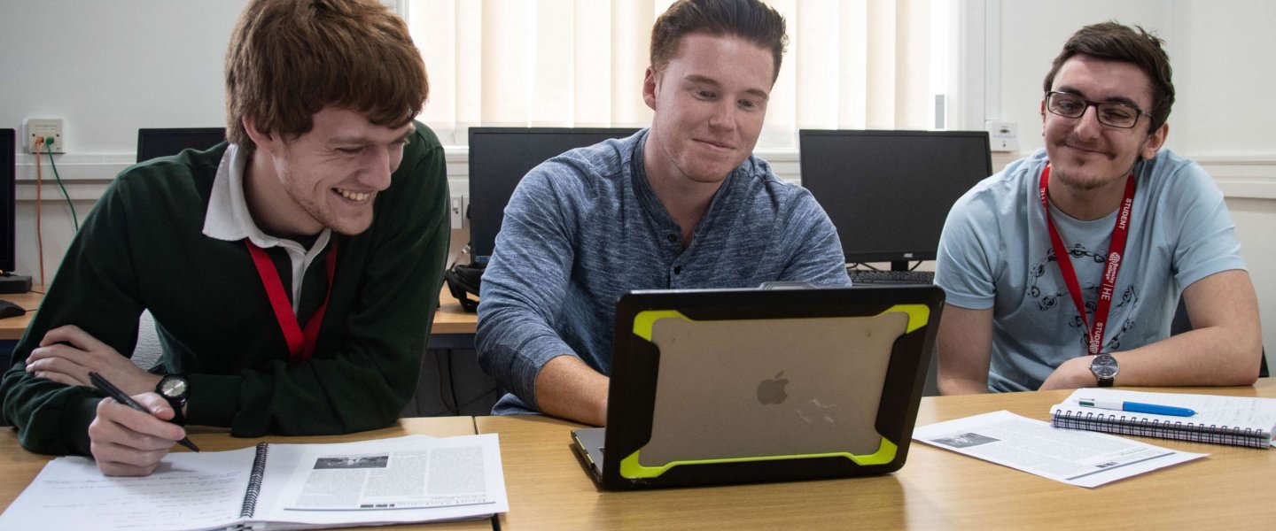 Three students looking at a laptop.