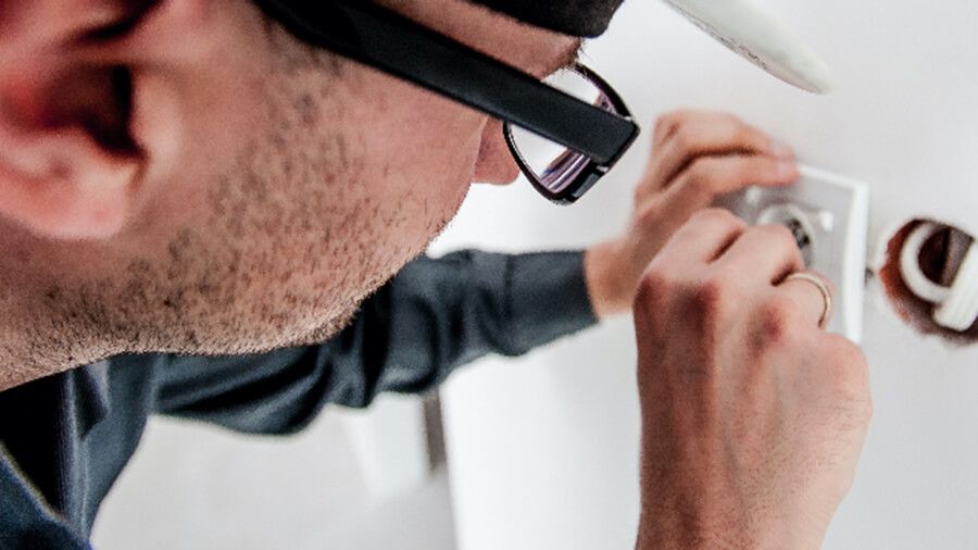 Man wearing glasses fixing plug on wall