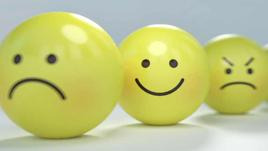 Three yellow balls, one with sad face, one with happy face and one with angry face