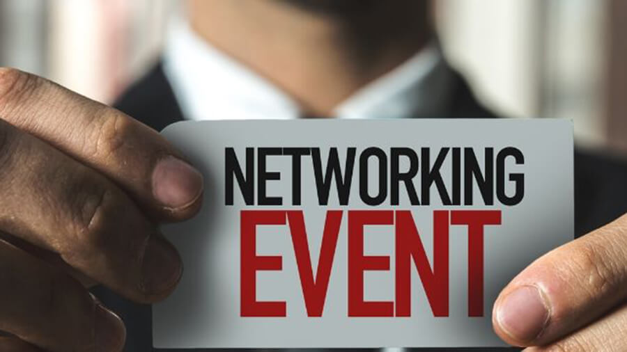 Man holding a small white card which says 'NETWORKING EVENT'