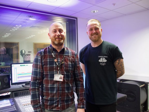 Two men in recording studio smiling at camera