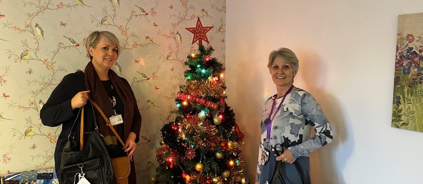 Nicola Thomson-Dewey (left) with Sue Tomlinson in front of a Christmas Tree holding handbags.