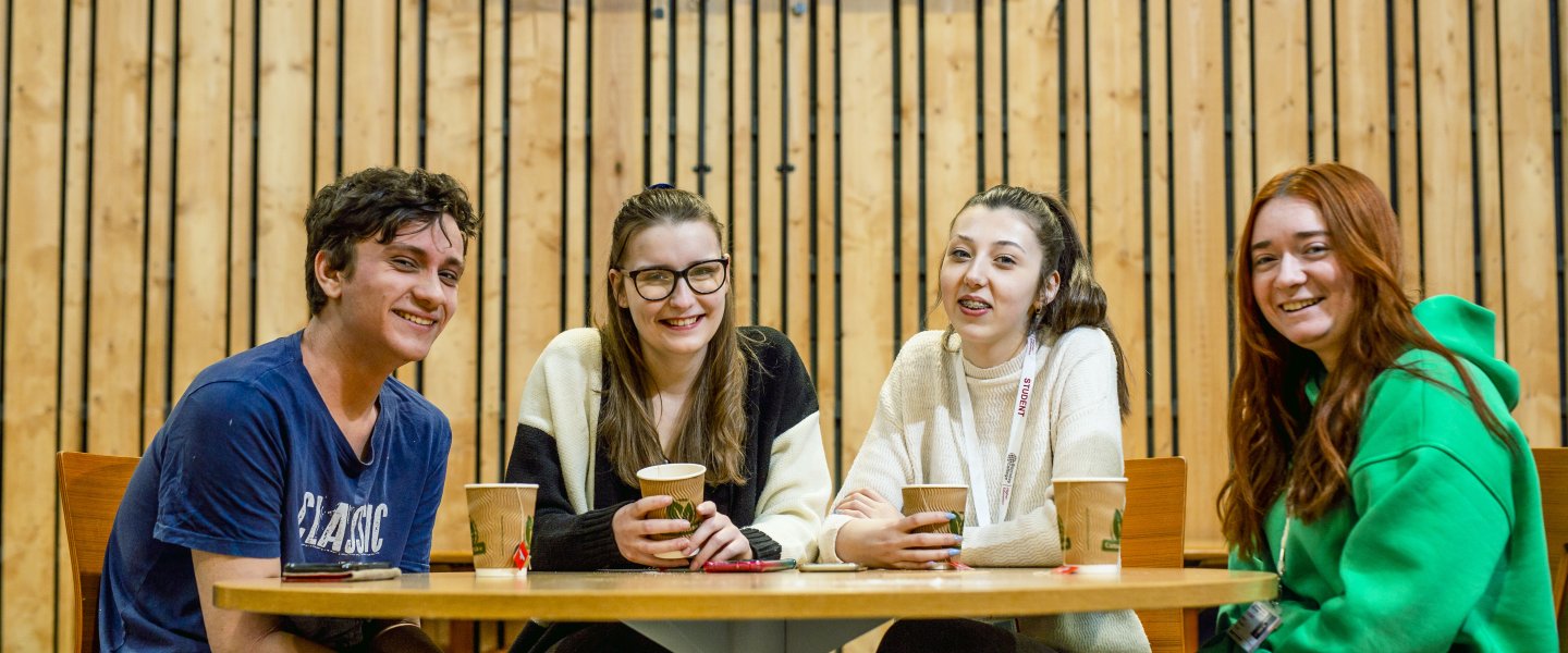 group of students smiling around a table with coffee cups