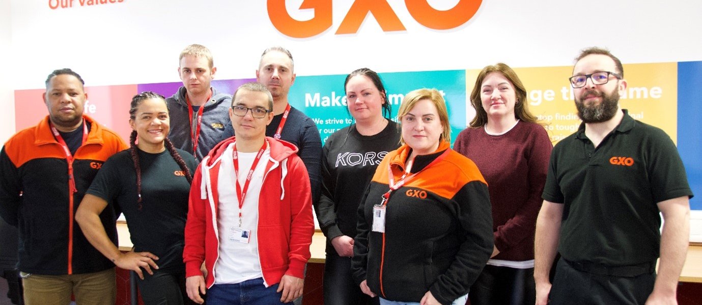 group of people stood in front of GXO logo
