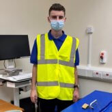 Picture of student Reece Crossley at his internship at Barnsley Hospital wearing high vis and a face mask