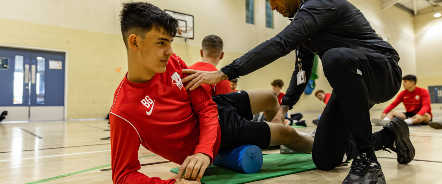A tutor helping a student complete exersise in sports gym