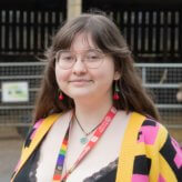 Student wearing cherry earrings and a yellow, pink and black cardigan with red lanyard
