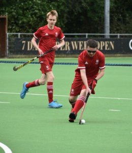 Rob Crosse running with the ball during a hockey game, wearing red uniform. 